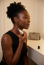 Load image into Gallery viewer, Gen Z African American woman applying a perfume rollerball to her neck before going out
